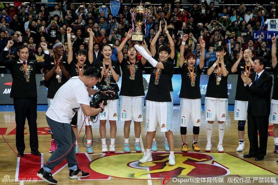 荣耀绽放:北京女篮问鼎总冠军,姚明见证王朝启航 中国篮协主席姚明面带微笑,弯下高大身躯将一枚金灿灿的总冠军奖牌挂在福尔斯颈上,福尔斯手捧鲜花与MVP奖杯,眼中闪烁着喜悦与自豪的光芒。