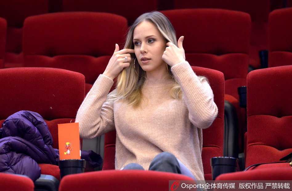 莫泰尤纳斯娇妻现场助阵,山东男篮激战江苏肯帝亚 宝莲娜在观赛间隙低头查看手机,或许是在记录这场比赛的精彩瞬间,又或是在与无法到场的亲友分享此刻的喜悦,背景是模糊的球场和观众。