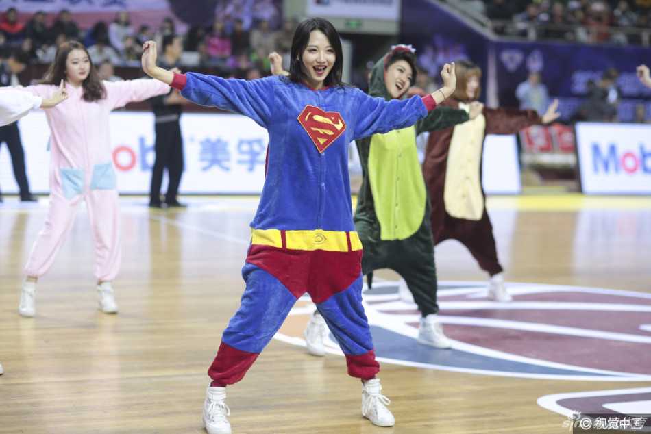 萌翻全场!当篮球宝贝变身睡衣女超人,赛场下的反差萌大作战 一位穿着红色超人披风睡衣的篮球宝贝,正对着镜头握拳鼓劲,眼神里带着还没睡醒的迷糊,却又努力做出严肃的表情,滑稽又可爱。