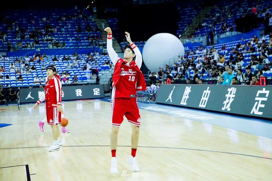 董力篮球赛场展锋芒:跨界名人赛首秀即成红队奇兵 董力在场上双手抱球做出投篮预备姿势,背景是座无虚席的东方体育中心看台,灯光璀璨气氛热烈