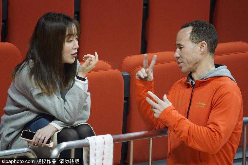 比赛进入暂停时间，美女裁判站在场边等待重新开球，她的背影与看台上密密麻麻的观众形成对比，红色的地板映衬着她的身姿，显得格外挺拔。