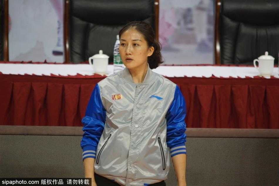 赛场中央，身穿深色裁判服的长发美女裁判目光如炬，她单手握拳，正准备吹响口中的哨子，严肃的神情与场边观众席上一位正在专注观看比赛的年轻女性形成了一种奇妙的静默呼应。
