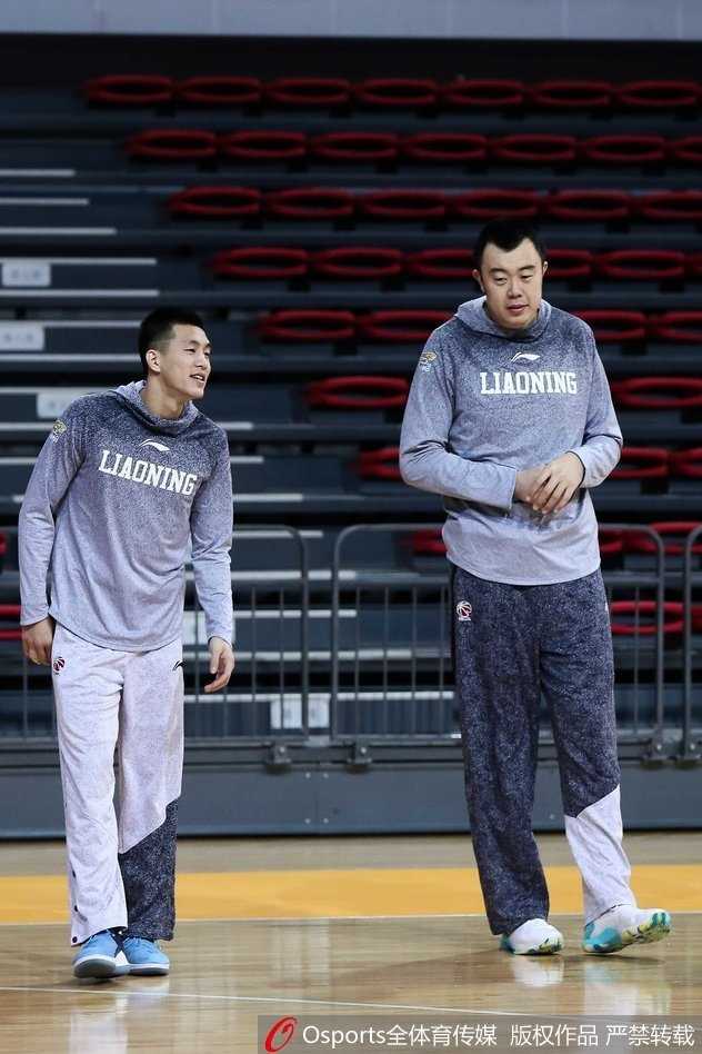 郭艾伦在韩德君身后搞怪地伸手触摸队友的肚子，大韩则一脸憨厚地回头，眼神里满是“老大哥”对调皮小弟的宠溺与无奈