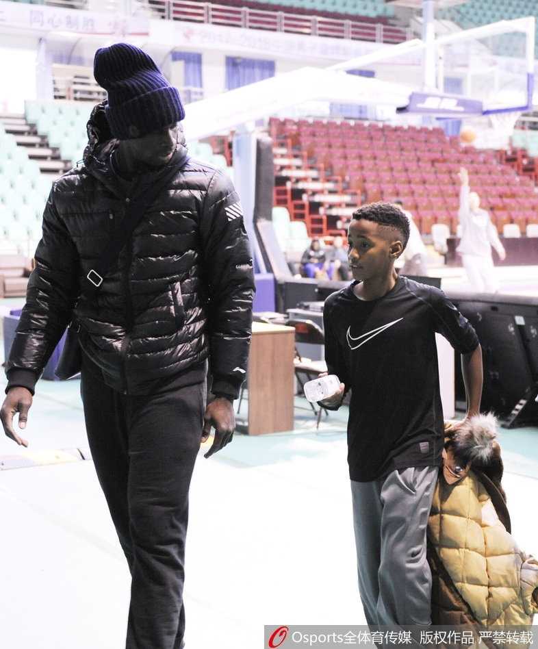 辽宁男篮赛前现温馨一幕 巴斯爱子场边秀球技 巴斯单手将儿子高高举起,让他摸高,父子俩笑容灿烂