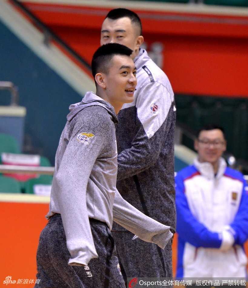 郭艾伦身披毛巾，转头与身旁的韩德君低声细语，眼神中透着专注，韩德君则认真倾听，兄弟间的默契尽在不言中。