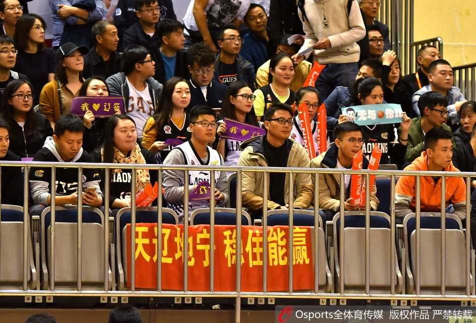 辽宁球迷看台展示巨幅TIFO，上面印着‘无畏远征’四个大字，四周蓝色助威棒闪烁如繁星，一名领喊的球迷正激情指挥着数百人的助威节奏。