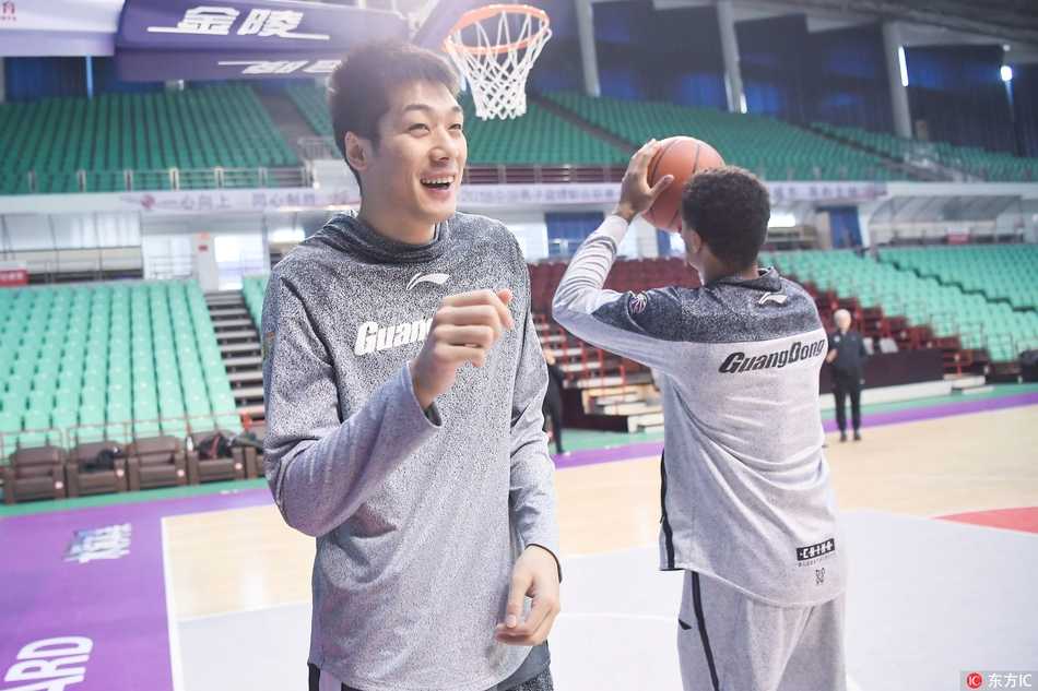 易建联篮下强起，肌肉线条绷紧，防守球员高举双臂形成遮天蔽日的干扰