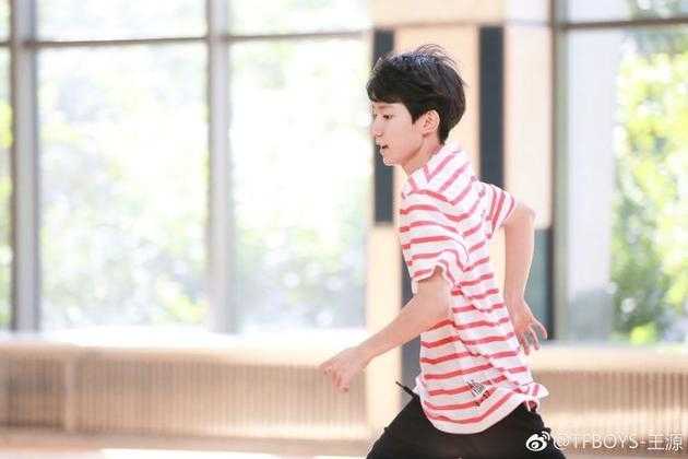 奔跑中的王源目光坚定望向前方，红白条纹衫在阳光下格外耀眼，黑色运动裤飞扬出流畅线条，仿若离弦之箭冲破时光