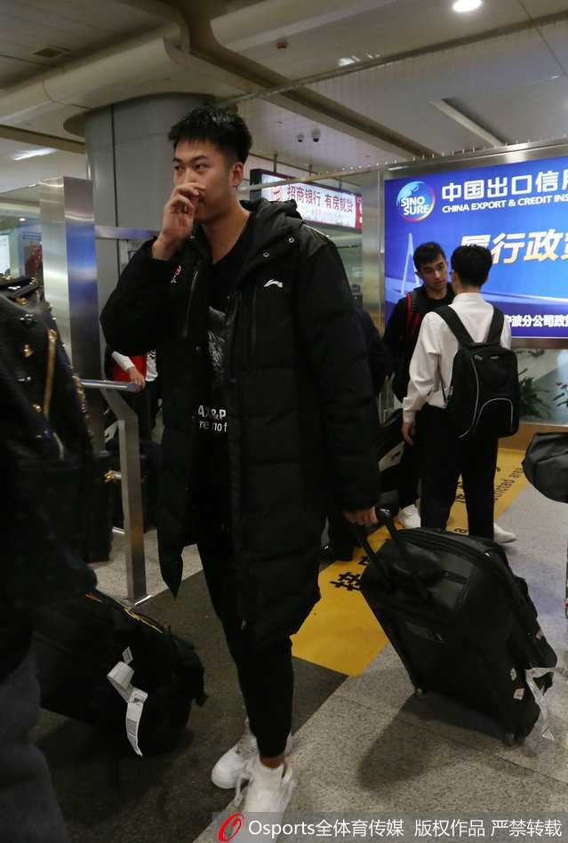 铁军新程:八一男篮抵宁波备战,青春风暴蓄势待发 面对镜头,主教练阿的江双手插兜,神情严肃地与身旁的领队交流,眉宇间透露出对新赛季困难准备的分析与思考。