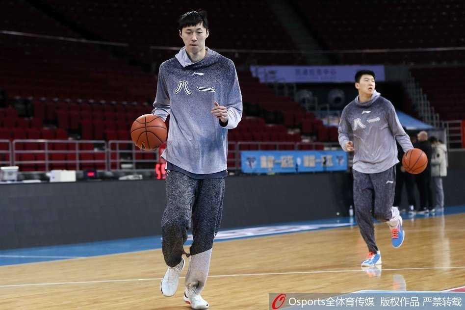 铁血继承者:王治郅督战第十八轮,八一队赛前挥汗备战 王治郅双手持球置于身前,正面指导一位八一队员,两人目光交汇,正在进行着关于战术跑位的深度交流,空气中弥漫着专注与严肃的气息。