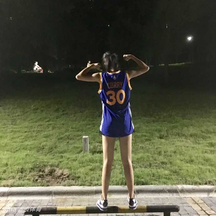 长腿女球迷的库里情节:篮球场边的迷人风景线 阳光洒在球馆木地板上,鲁西西ii身穿库里30号球衣回眸一笑,修长身影与篮筐构成一幅活力画卷