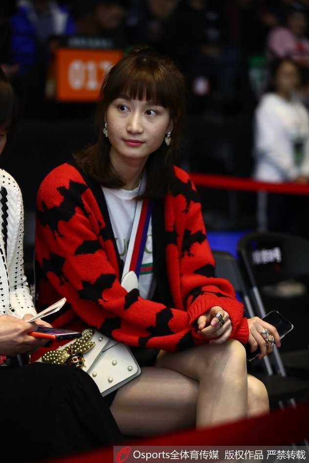 闪耀鹏城:周鹏爱妻领衔太太团助阵,二〇一八CBA全明星赛南区明星队力克北区 太太团成员之一在场边专注地观看比赛,手中拿着CBA官方应援棒,脸上洋溢着开心的笑容,完全沉浸在比赛的紧张与欢乐氛围中。