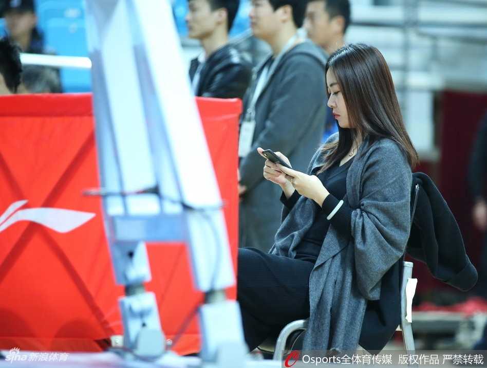 一位穿着时尚的短发女球迷侧身而立，在赛场背景的映衬下，轮廓分明，显得既酷又充满活力