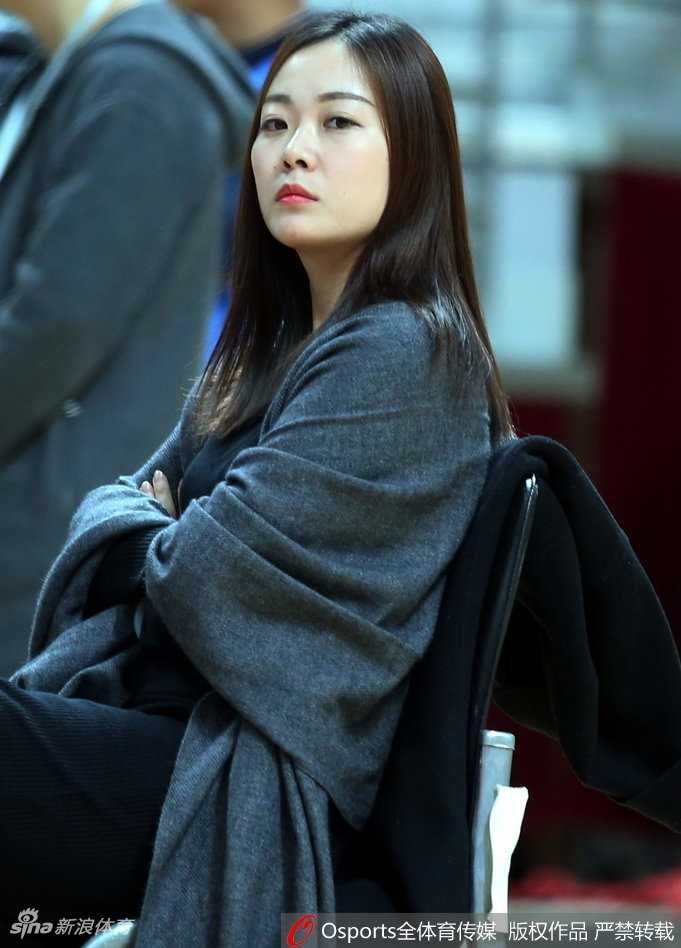 一位气质清新的女球迷坐在看台上，目光越过赛场，嘴角带着浅浅的笑意，仿佛为支持的队伍暗暗加油