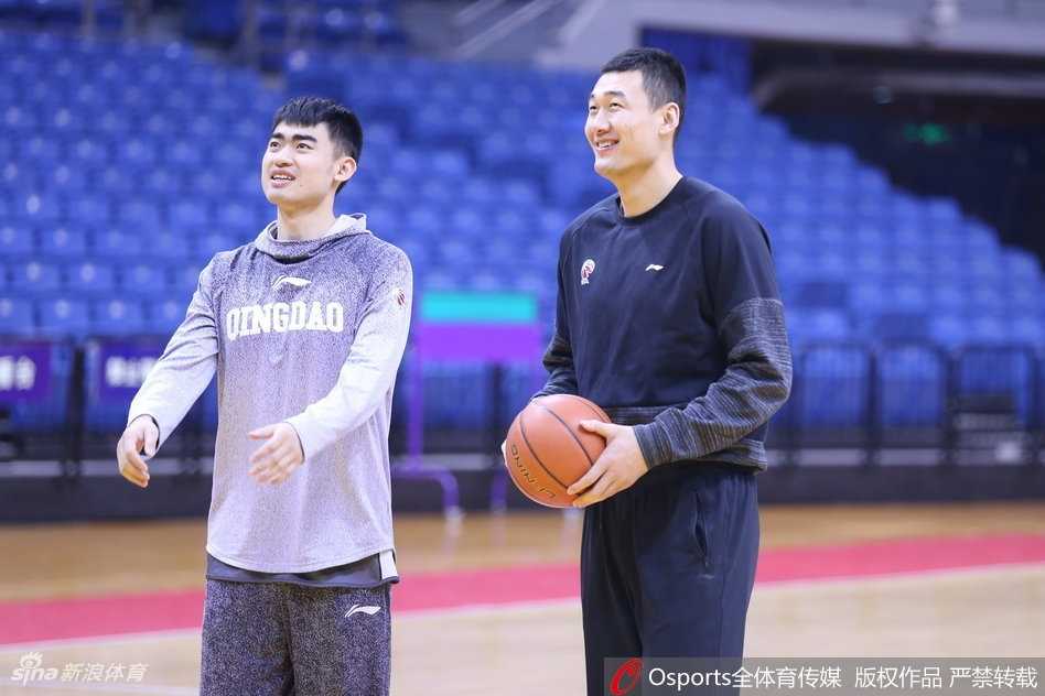 巩晓彬神情专注地指导队员战术，李秋平双手抱胸在一旁微笑倾听，两位山东篮坛的标志性人物在训练场上演温情一幕。