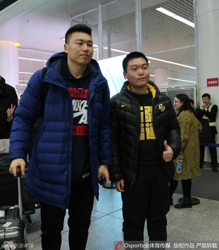 李根被热情的球迷层层包围，他手拿签名笔，正低头为一位身穿他球衣的小球迷签名，脸上挂着亲切的笑容。