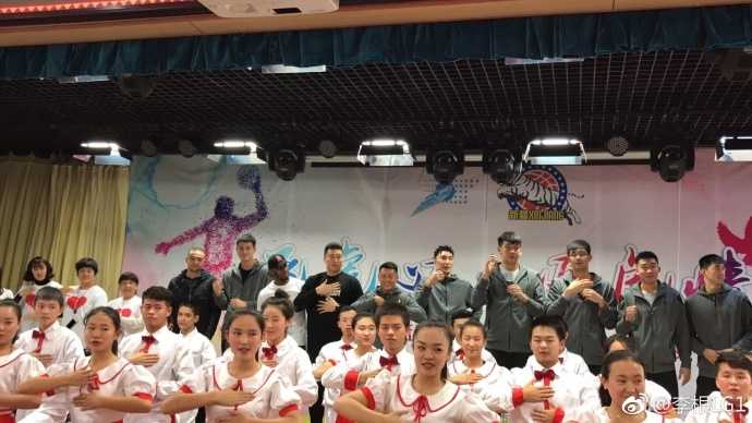 可兰白克蹲在孩子们中间,与大家一起做互动游戏,他的脸上满是温暖的笑意,孩子们也沉浸在欢乐的氛围中,画面温馨和谐