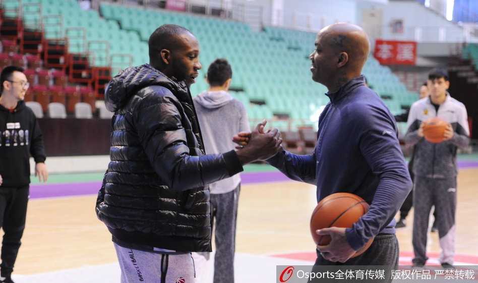 训练场上，哈德森露出标志性的憨厚笑容，马布里侧身与其交谈，两人身后的篮球架和队友构成背景，整个画面充满大战前夕难得的轻松与默契。