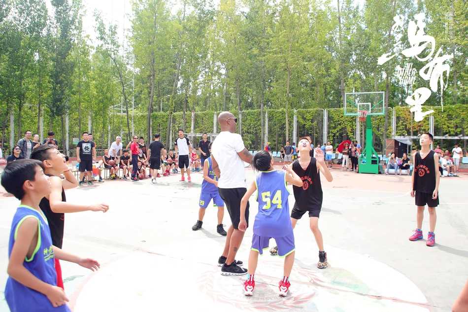 马布里校园行化身“暖心教头”,与篮球少年上演萌趣“尬球”对决 在球场上,一名勇敢的小学生正试图突破马布里的防守,老马则张开双臂,作出认真防守的姿态,场面既温馨又充满竞技的趣味。