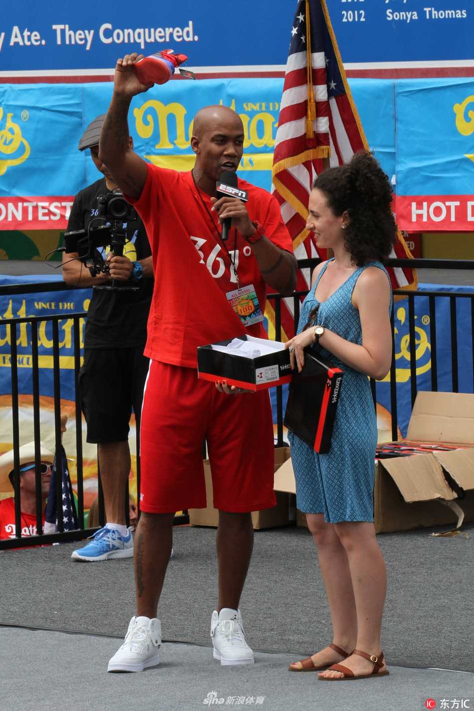 马布里独立日返乡宣传个人品牌 热狗大赛变身移动广告位 镜头拉近,马布里神情专注地看向比赛方向,左手下意识地指向自己胸前那个醒目的个人品牌商标,仿佛在告诉镜头后的观众:今天的主角除了热狗,还有我脚下的这双鞋。