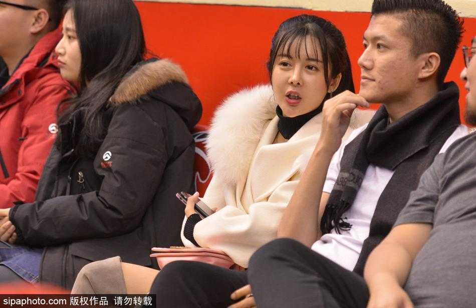 齐鲁冬夜,那一抹温柔热爱:聚焦CBA赛场上的女性力量 一位面容清秀的女球迷披散着长发,双手轻托脸颊,眼神专注地望向赛场中央,仿佛此刻世界只剩下她与那片熟悉的篮球场。