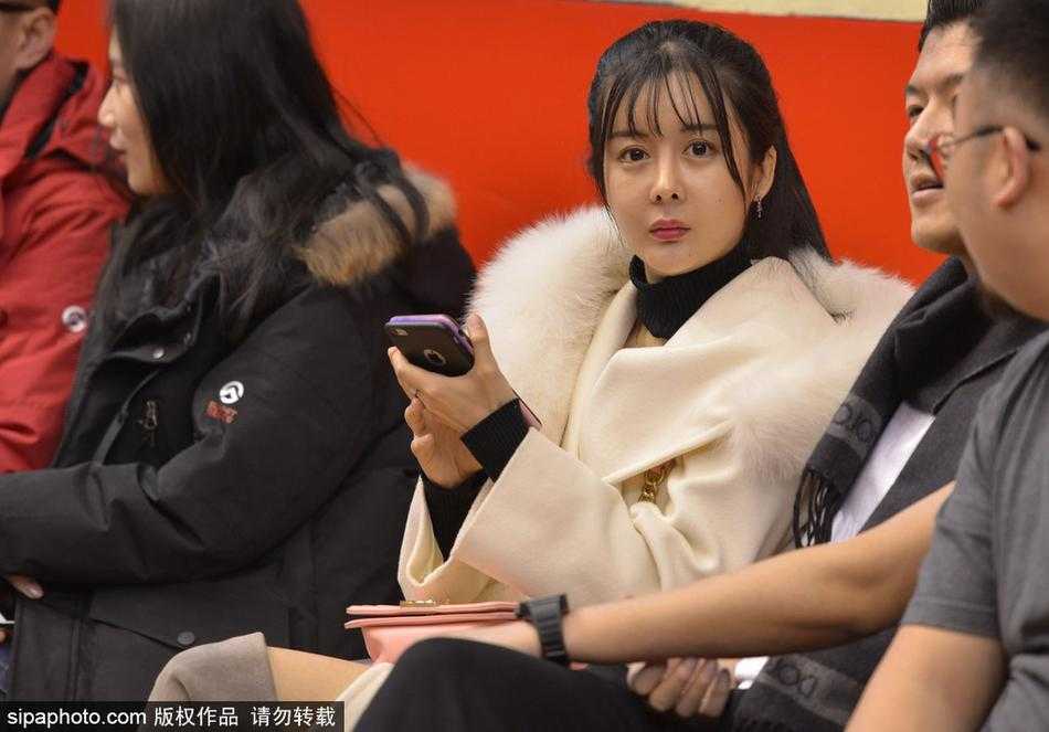 齐鲁冬夜,那一抹温柔热爱:聚焦CBA赛场上的女性力量 一位戴着眼镜、文静秀气的女球迷,双手轻轻放在身前,脸上洋溢着满足而温暖的微笑,在这充满对抗的球馆里,如同一阵和煦的春风。