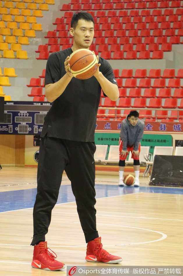 山东队训练场景全景，球员们正在进行战术演练，每个人都专注于教练的指令，整个球馆充满了积极紧张的备战气氛。