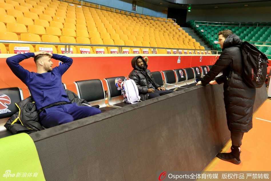 丁彦雨航在训练间隙裹着厚厚的棉服，双手缩在袖口里，眼神中带着一丝慵懒与好奇，像一只在寒冷冬日里刚从窝里探出脑袋的小松鼠，憨态可掬。