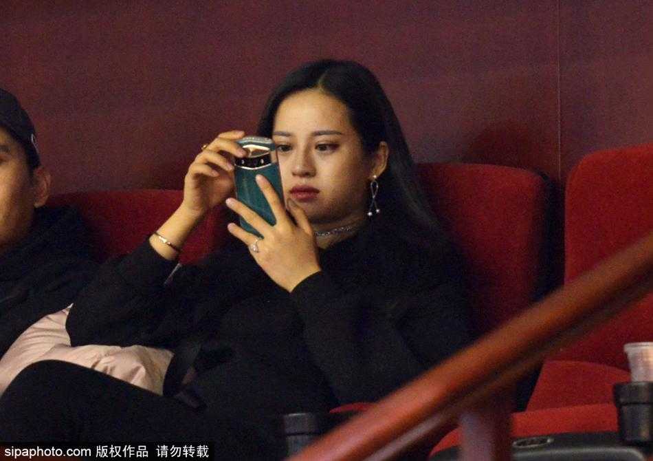 一位面容清秀的山东女球迷，身披深色外套，在全神贯注地观看比赛，她的眼神里充满了对主队获胜的渴望与期待。