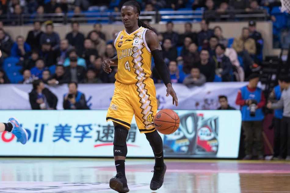 广厦队李京龙在底角命中外线三分后，右手握拳高举，脸上洋溢着兴奋的笑容，身旁的江苏队防守球员面露无奈之色。