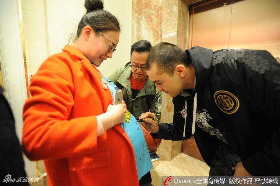 李根手拿手机专心致志地为台上的队友拍照，神情十分投入